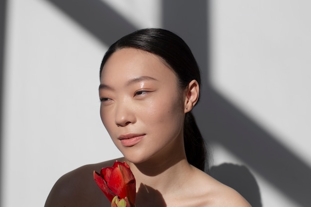 Belle femme asiatique posant tenant une rose avec une peau parfaite