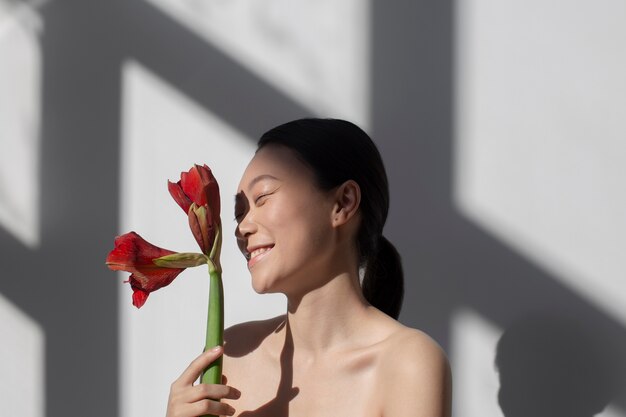 Belle femme asiatique posant tenant une rose avec une peau parfaite