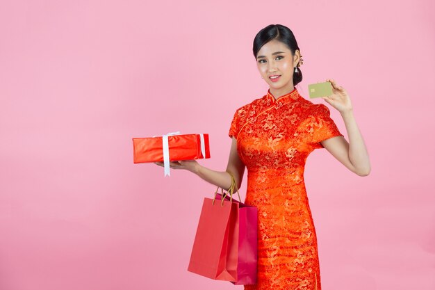 Belle femme asiatique sourire heureux et montrer la carte de crédit au nouvel an chinois sur fond rose.