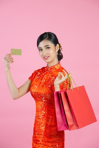 Belle femme asiatique sourire heureux et shopping au nouvel an chinois sur fond rose.