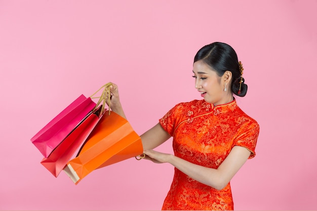 Belle femme asiatique sourire heureux et shopping au nouvel an chinois sur fond rose.