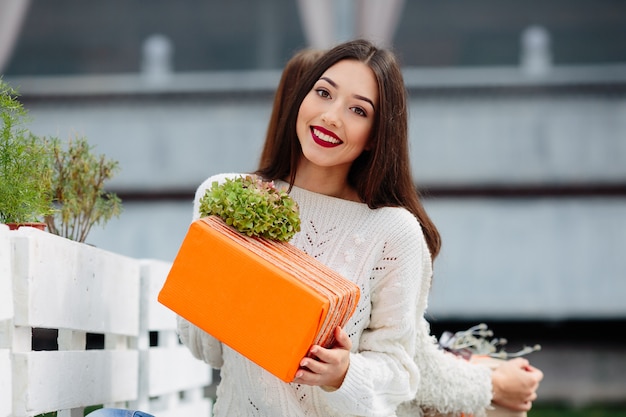 Belle femme assise sur un banc et tenant dans ses mains un cadeau