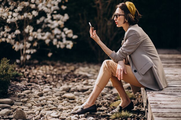 Belle femme assise dans l'arrière-cour et à l'aide de téléphone