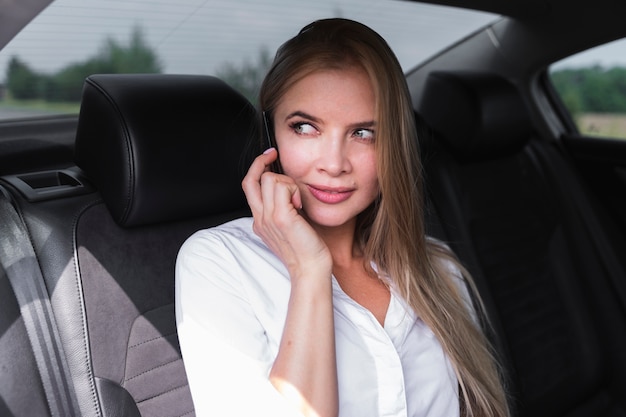 Belle femme assise dans la voiture et à la recherche de suite