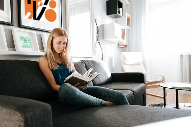 Belle femme assise et lisant un livre à la maison