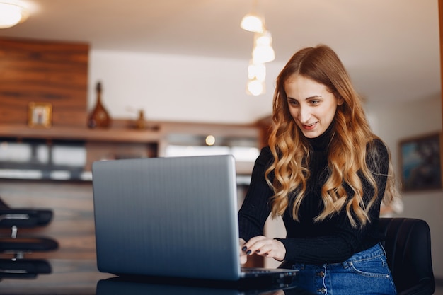 Belle femme assise à la maison avec un ordinateur portable