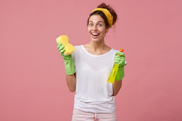 Belle femme au foyer avec bandeau jaune et T-shirt blanc tenant une vadrouille et un spray de lavage à la bonne humeur et souhaite faire le ménage de printemps dans sa maison