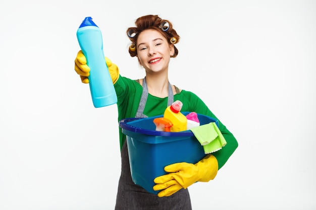 Belle femme au foyer détient des outils de nettoyage et montre une bouteille