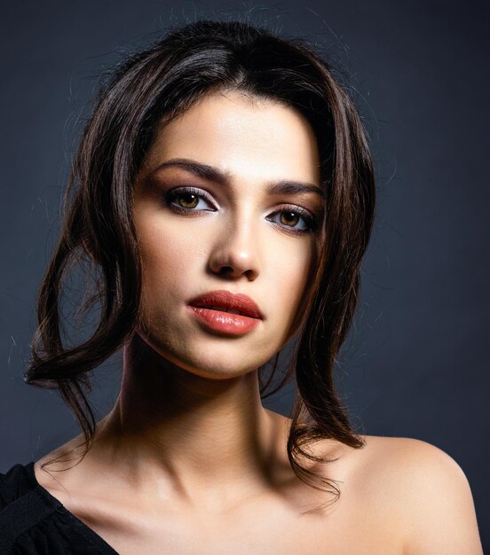 Belle femme aux cheveux bruns. Modèle attrayant aux yeux bruns. Mannequin avec un maquillage smokey. Closeup portrait d'une jolie femme. Coiffure créative.