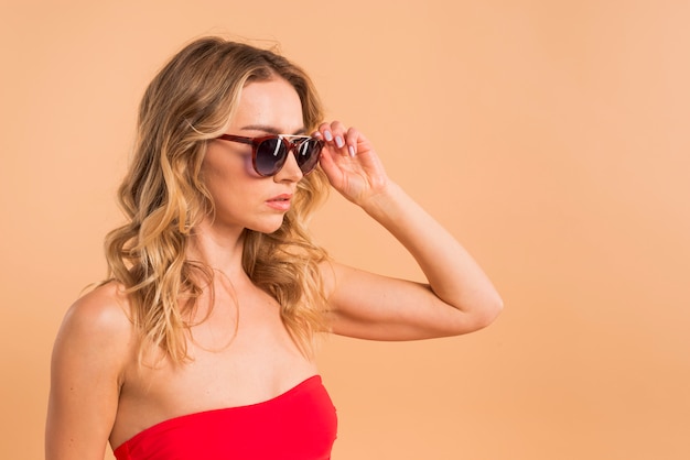 Belle femme aux longs cheveux blonds en haut rouge et lunettes de soleil