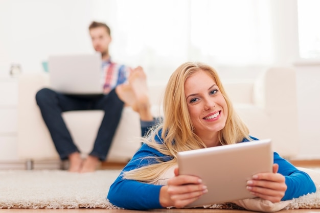 Belle femme blonde à l'aide de tablette numérique et se détendre sur capet à la maison