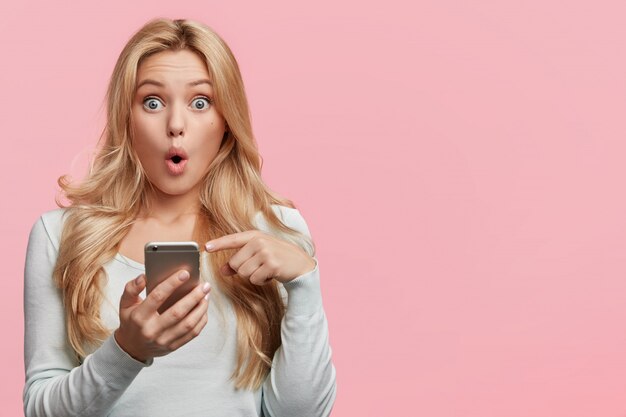 Belle femme blonde avec une chemise blanche tenant le téléphone