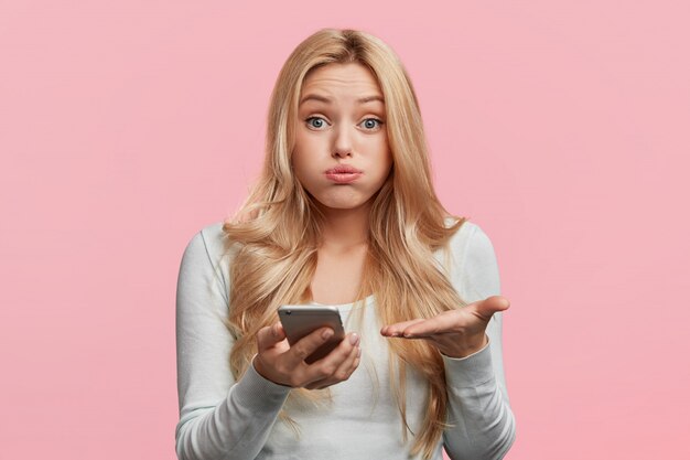 Belle femme blonde avec une chemise blanche tenant le téléphone