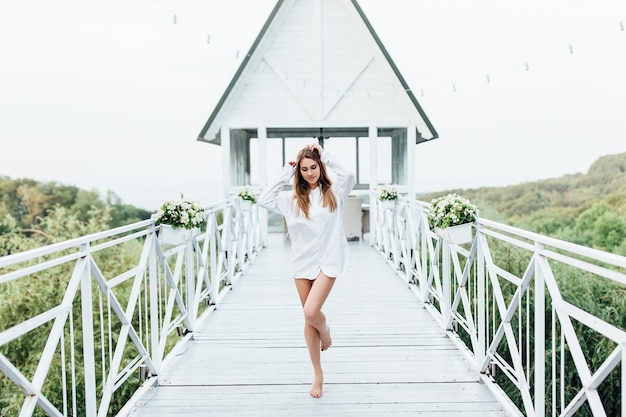 Photo gratuite belle femme blonde en chemise d'homme sur la terrasse d'été reposant dans un complexe de luxe. posant pour l'instagram.