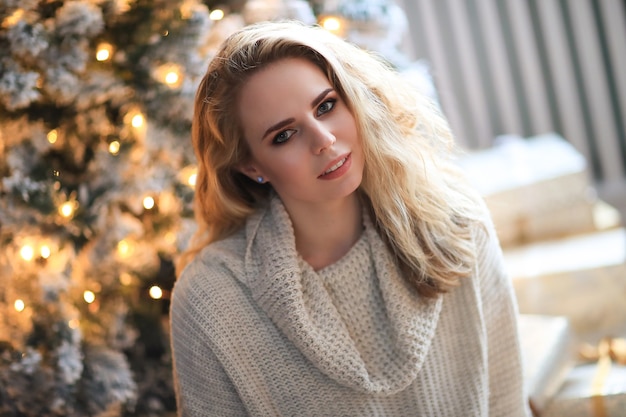 Belle femme blonde à côté de l'arbre de Noël.