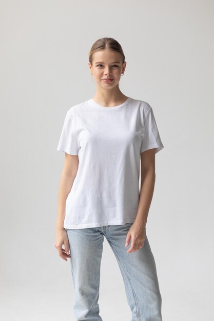 Une belle femme blonde dans un t-shirt blanc et un jean bleu posant sur un fond blanc