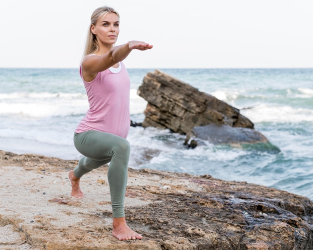 Belle femme blonde faisant du yoga à la plage