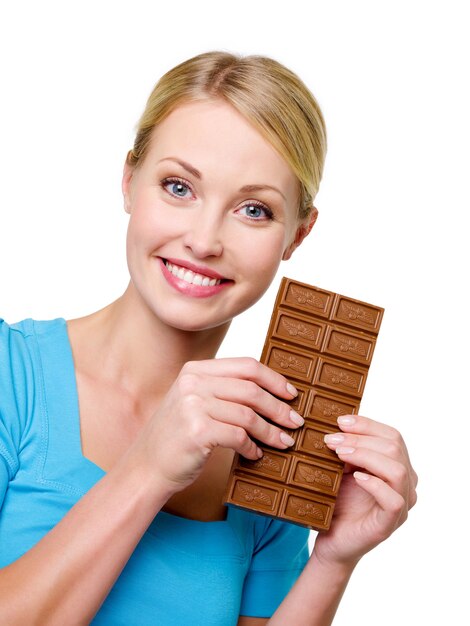 Belle femme blonde heureuse tenant la douce barre de chocolat noir près de son visage