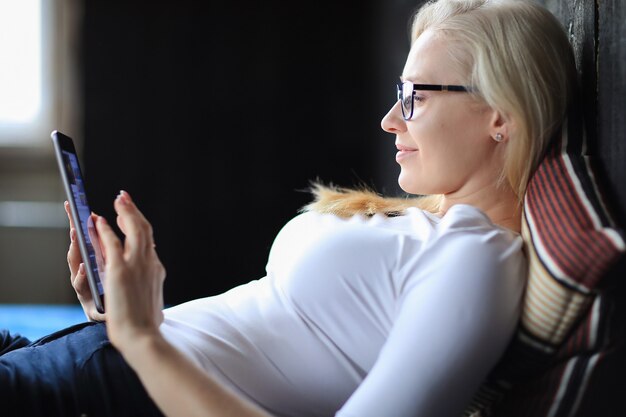 Belle femme blonde avec des lunettes posant en chemise blanche