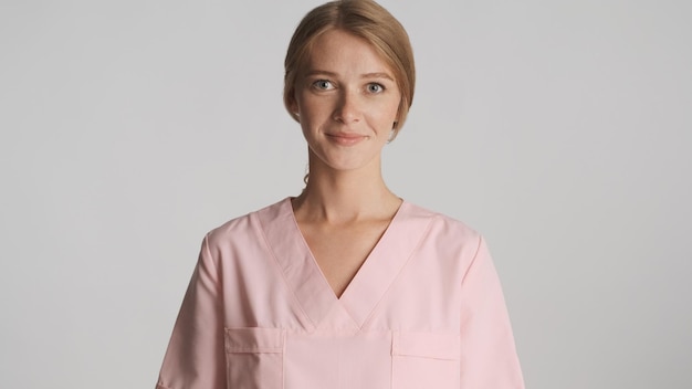 Photo gratuite belle femme blonde médecin en uniforme se présentant à la caméra isolé sur fond blanc