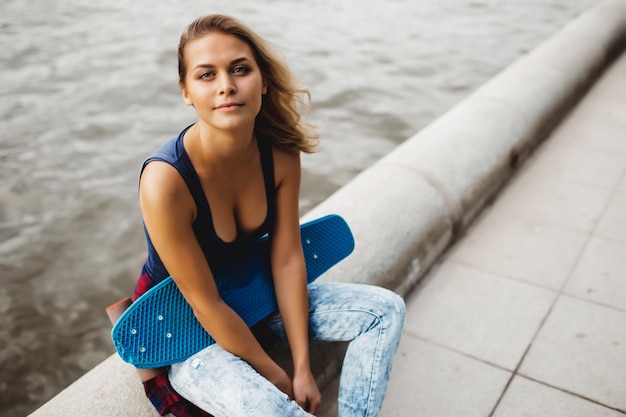 Photo gratuite belle femme blonde posant avec une planche à roulettes