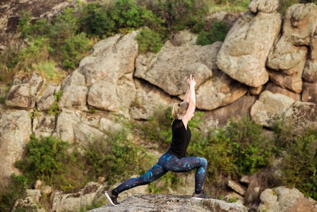 Belle femme blonde pratiquant le yoga asanas sur rocher dans le canyon