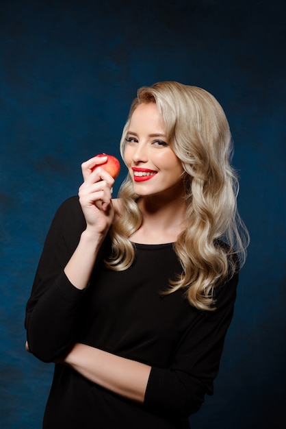 Belle femme blonde en robe noire tenant la pomme