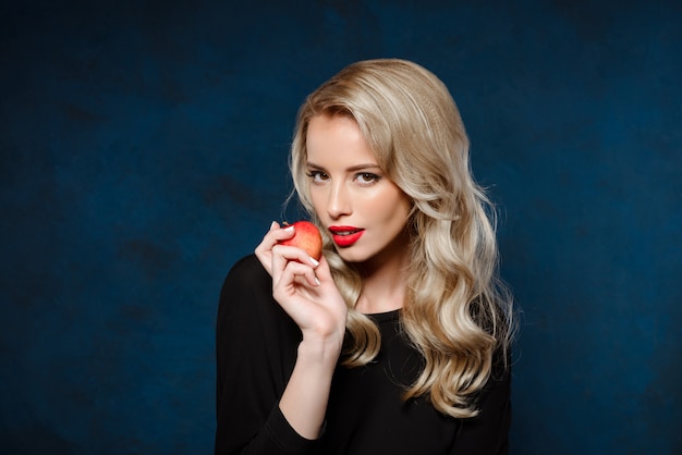 Belle femme blonde en robe noire tenant la pomme