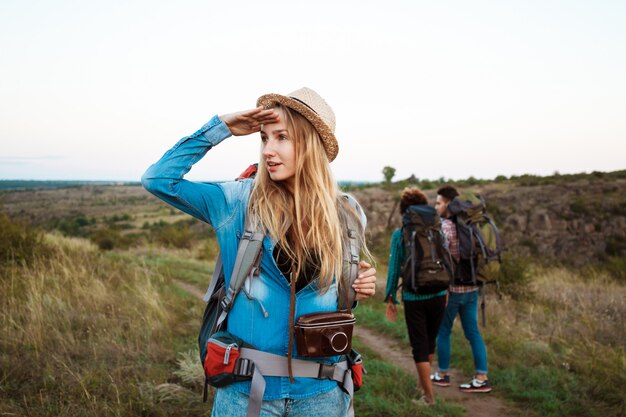 Belle femme blonde souriante, regardant à distance, fond de touristes amis