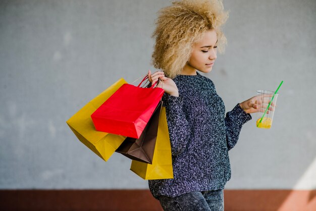 Belle femme blonde tenant des sacs et des sacs en papier