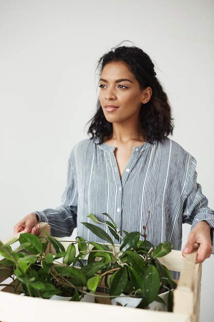 Belle femme botaniste souriant tenant la boîte avec des plantes