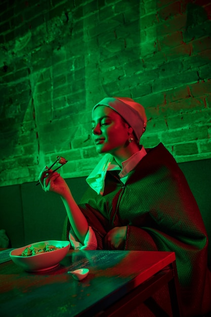 Belle femme avec une boucle d'oreille perle prenant le déjeuner dans un café moderne