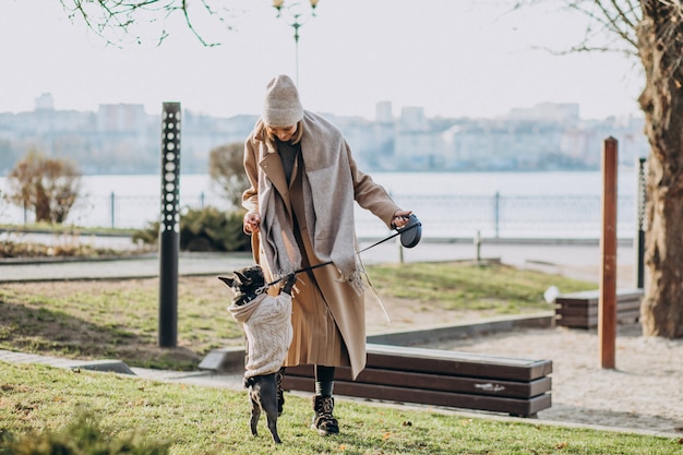 Belle femme avec bouledogue français marchant dans le parc