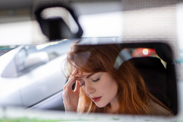 Belle femme bouleversée assise dans une automobile et pleurant rupture et tristesse