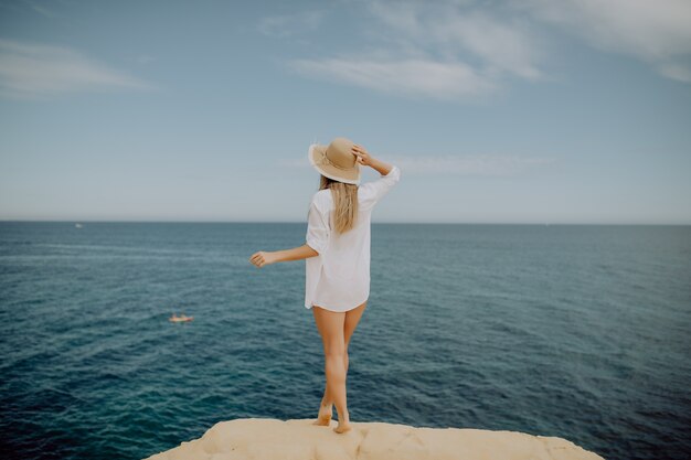 Belle femme bronzée avec les mains levées en regardant l'océan