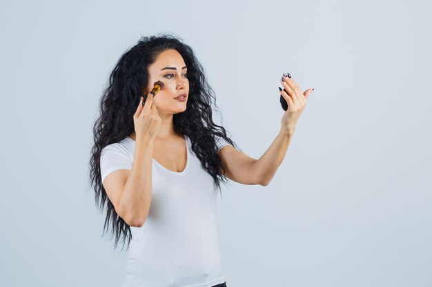 Belle femme brune avec un pinceau de maquillage