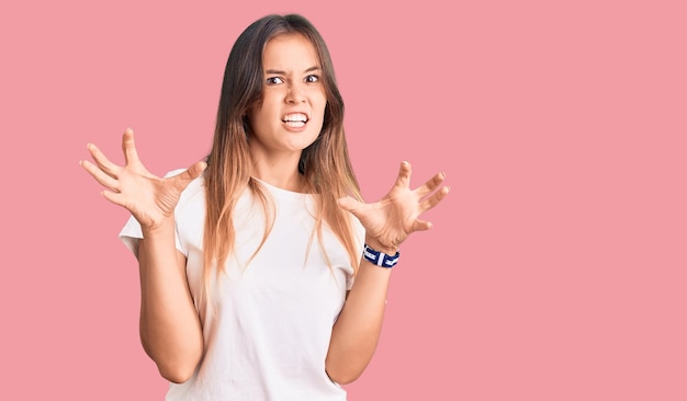 Photo gratuite belle femme caucasienne portant un t-shirt blanc décontracté souriant drôle faisant un geste de griffe comme chat expression agressive et sexy