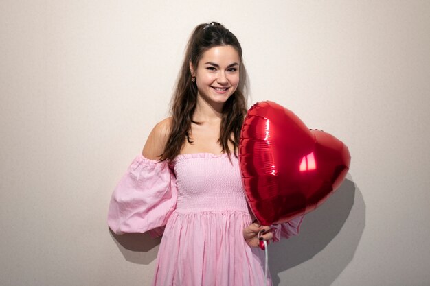 Belle femme célébrant la Saint-Valentin dans une robe rose avec des ballons