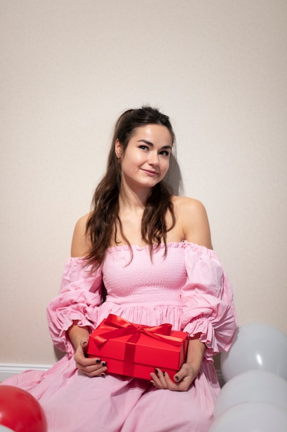 Photo gratuite belle femme célébrant la saint valentin vêtue d'une robe rose avec des ballons et présente