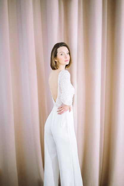 Belle femme en chemise blanche et pantalon debout et regardant dans la chambre avec perle