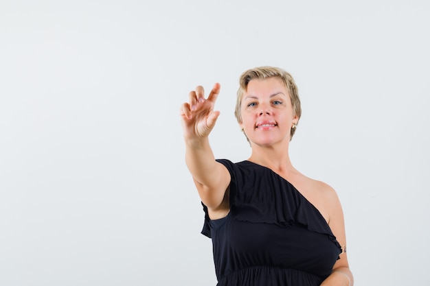 Belle femme en chemisier noir posant comme montrant une bouteille de pilules