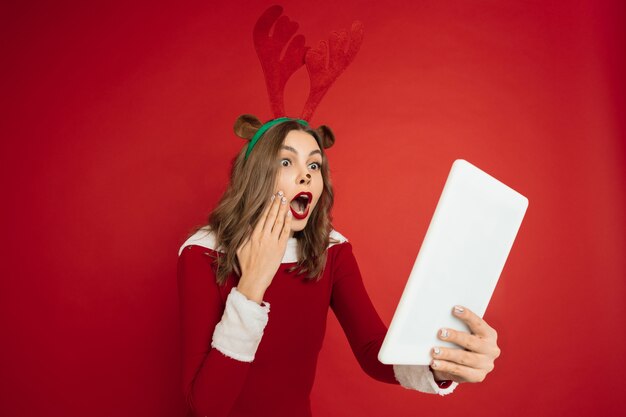 Belle femme comme le cerf de Noël isolé sur le concept de mur rouge