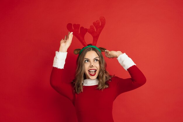 Belle femme comme le cerf de Noël isolé sur le concept de surface rouge des vacances d'humeur d'hiver du nouvel an