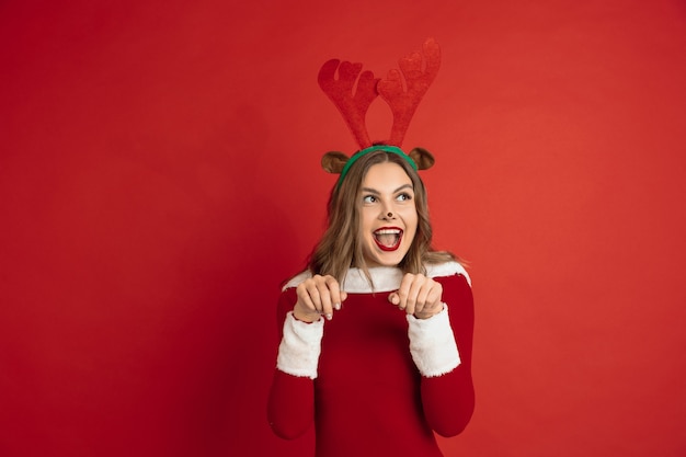 Belle femme comme le cerf de Noël isolé sur le concept de surface rouge des vacances d'humeur d'hiver du nouvel an