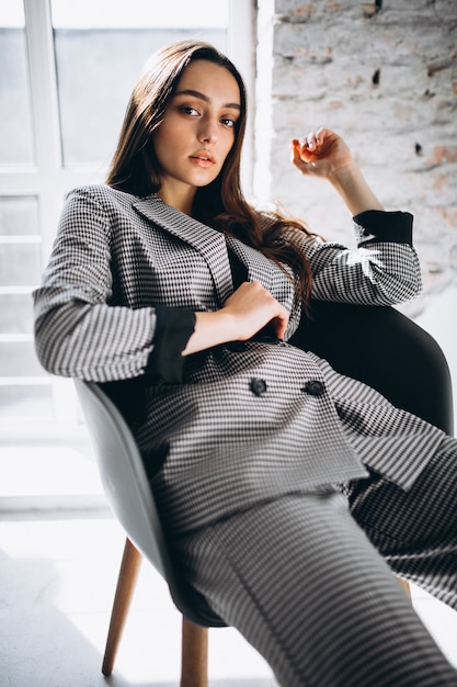 Belle femme en costume d'affaires assis sur une chaise