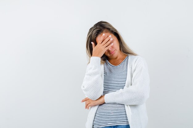 Belle femme couvrant le front avec la main dans la veste et à la perplexité. vue de face.