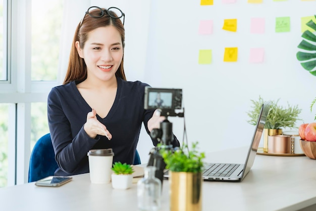 Belle femme créative intelligente asiatique présente au concept d'idées de blogueur de caméra