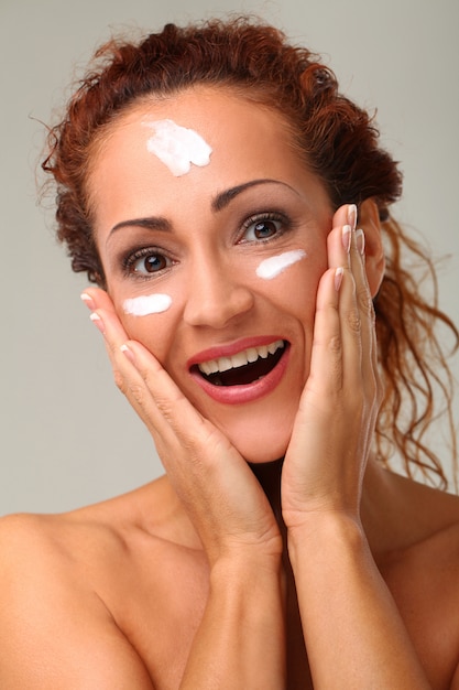 Belle femme avec de la crème sur le visage