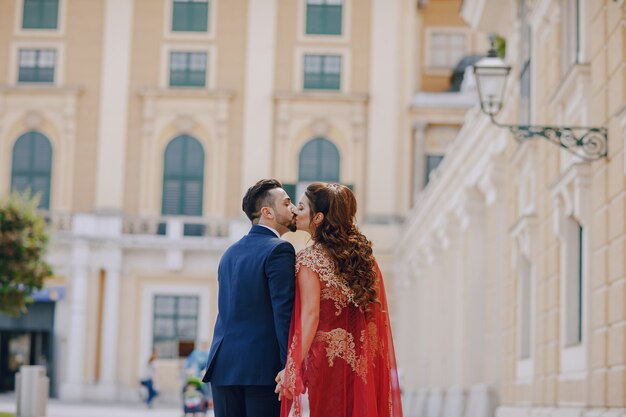 Belle femme dans une longue robe rouge se promène dans la ville avec son mari