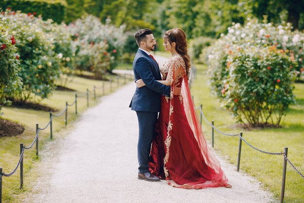 Belle femme dans une longue robe rouge se promène dans la ville avec son mari